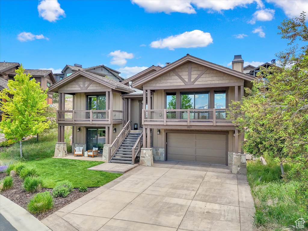 View of front of property with an attached garage, stairway, driveway, a front lawn, and board and batten siding