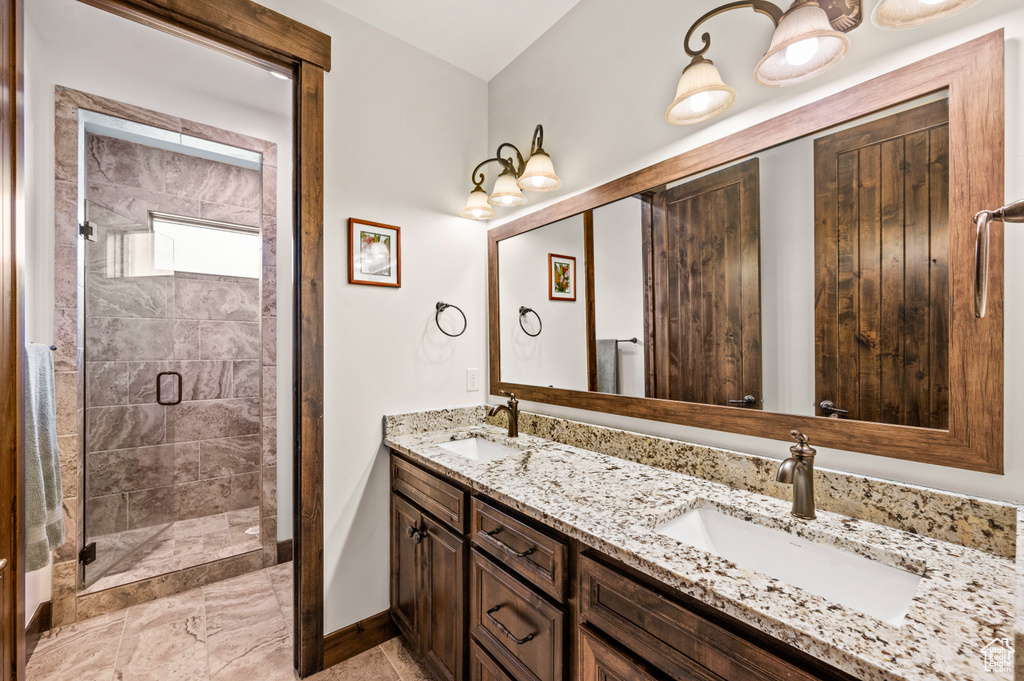 Bathroom featuring double vanity, tiled shower, and tile floors