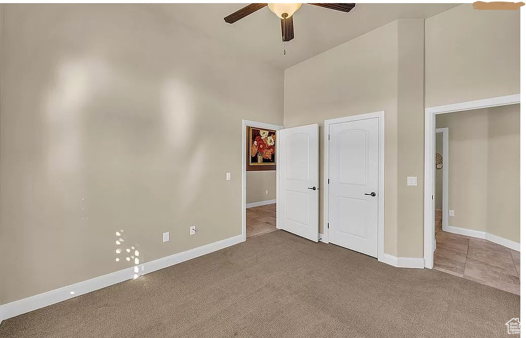 Unfurnished bedroom featuring high vaulted ceiling, light carpet, and ceiling fan