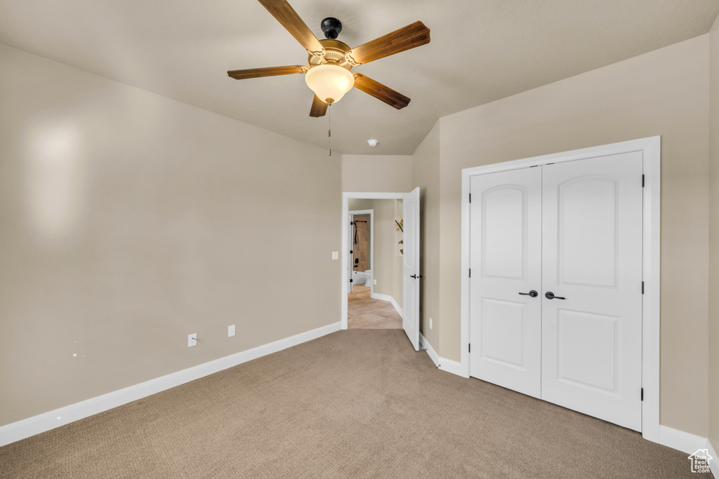 Unfurnished bedroom featuring ceiling fan, a closet, and light carpet