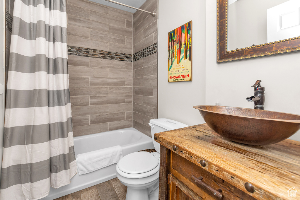Full bathroom with shower / bathtub combination with curtain, vanity, toilet, and hardwood / wood-style floors