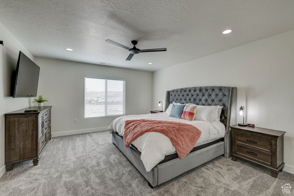 Bedroom featuring light carpet, a textured ceiling, and ceiling fan