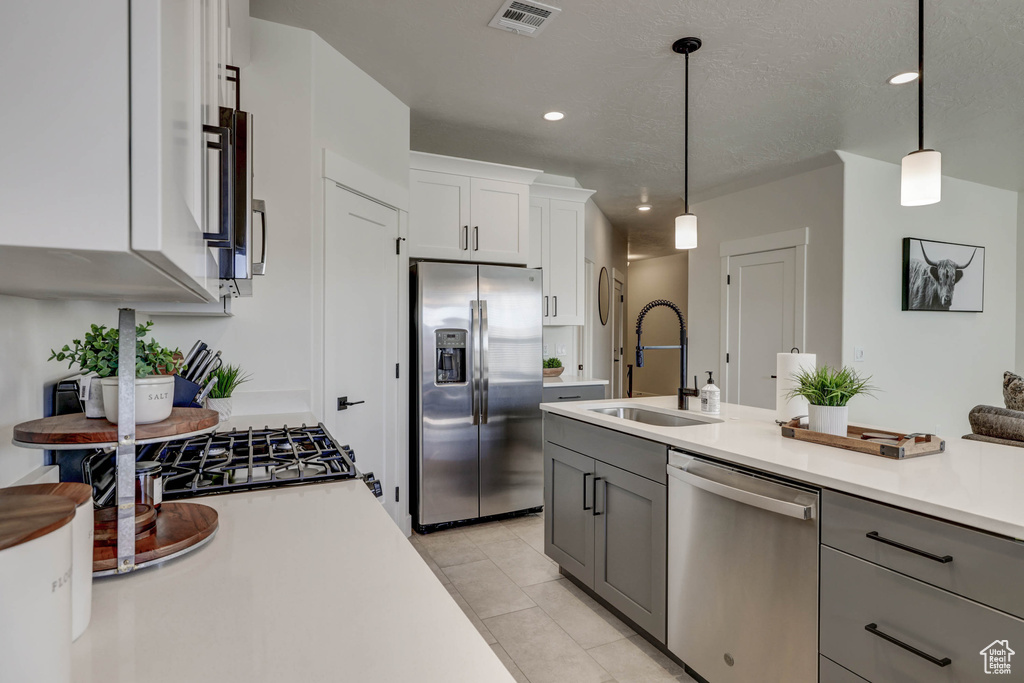 Kitchen featuring decorative light fixtures, white cabinets, gray cabinets, and stainless steel appliances