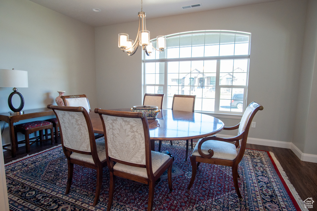 Dining room with a notable chandelier and dark hardwood / wood-style floors