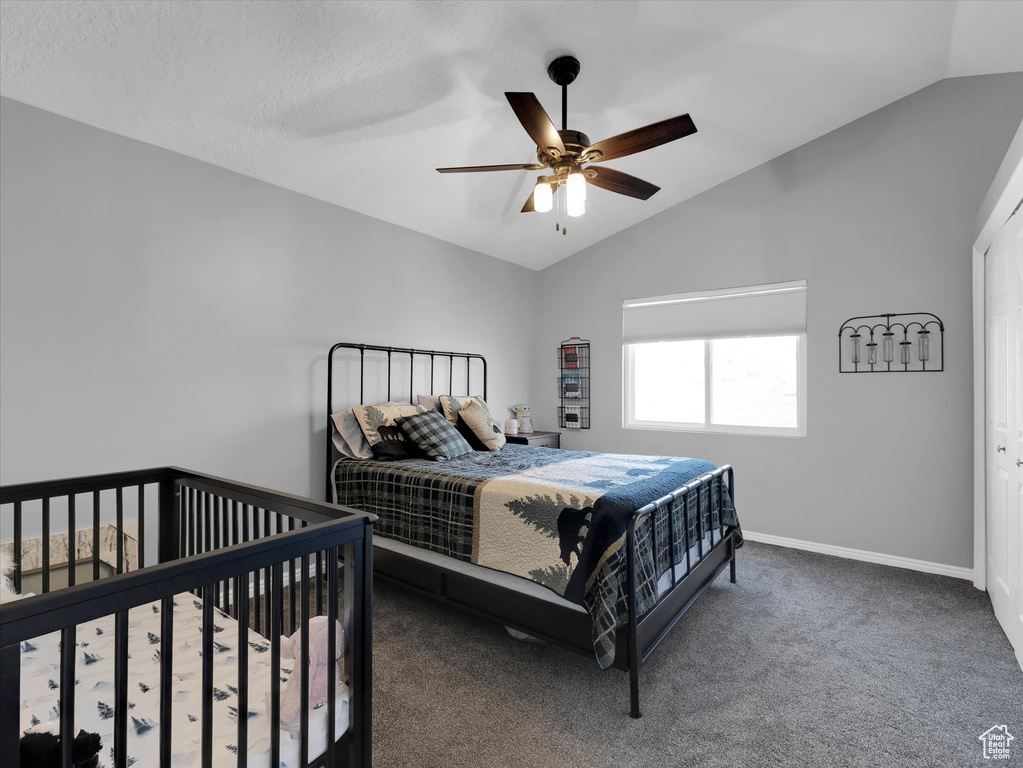 Bedroom with ceiling fan, lofted ceiling, dark colored carpet, and a closet