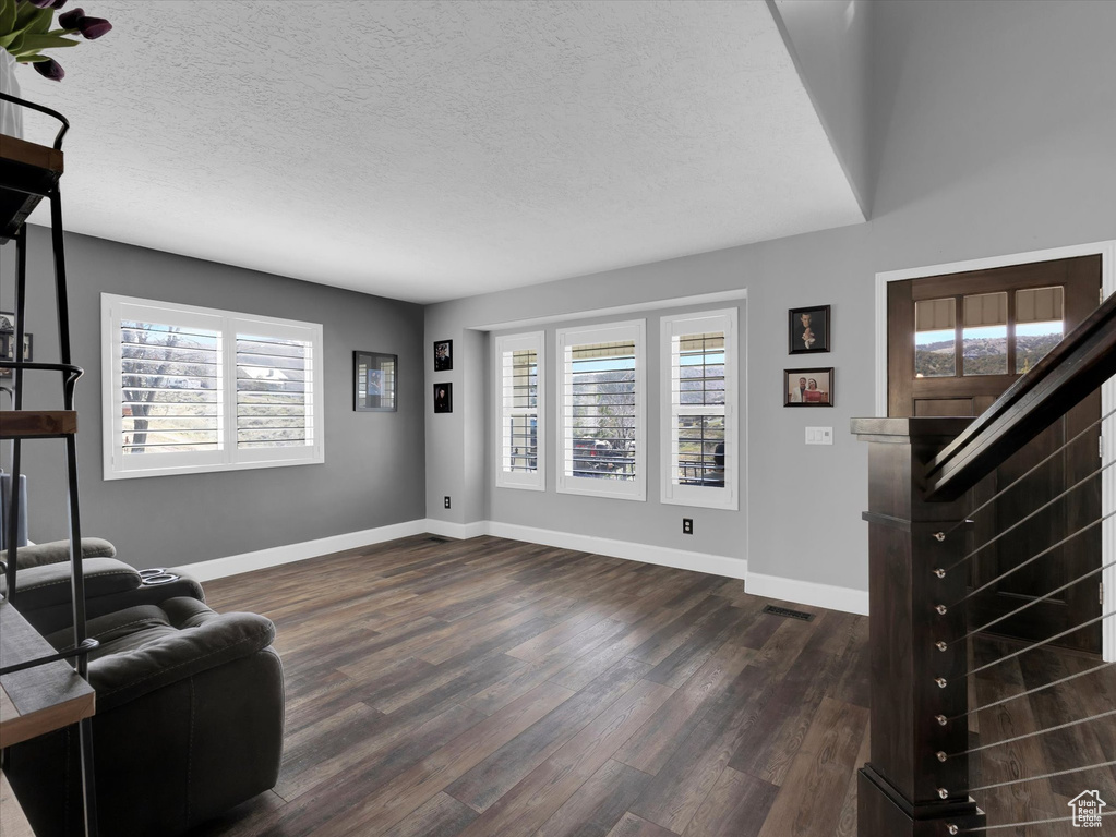 Living room featuring dark hardwood / wood-style flooring and a textured ceiling