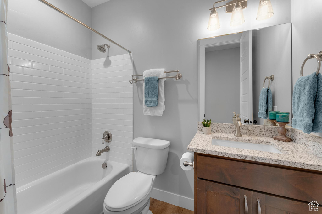 Full bathroom with toilet, hardwood / wood-style flooring, vanity, and tiled shower / bath