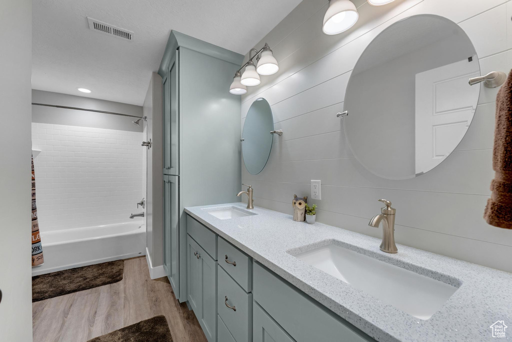 Bathroom featuring double sink vanity, shower / tub combination, and hardwood / wood-style floors