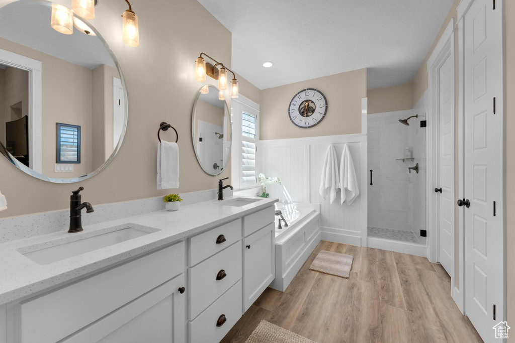 Bathroom featuring plus walk in shower, hardwood / wood-style floors, and dual vanity
