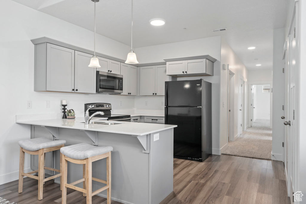 Kitchen featuring stainless steel appliances, gray cabinets, kitchen peninsula, and wood-type flooring
