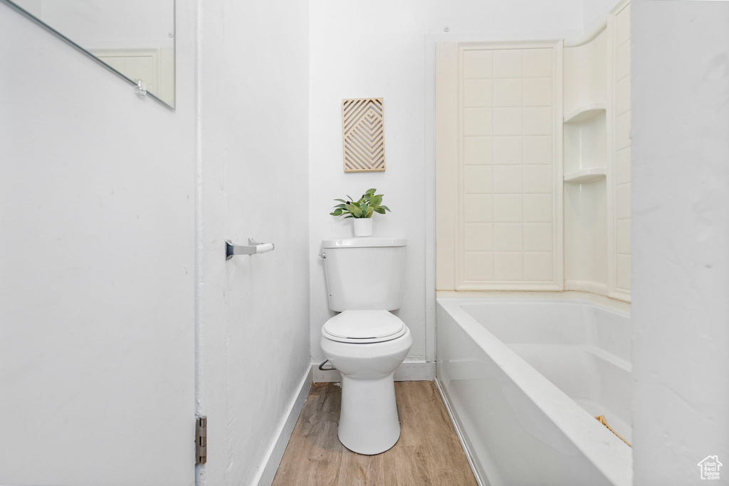 Bathroom with bathtub / shower combination, toilet, and hardwood / wood-style flooring