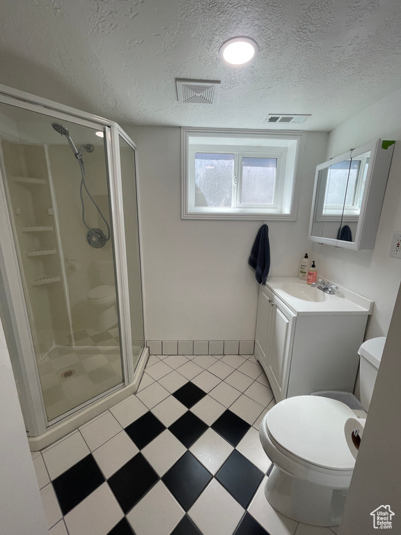 Bathroom with toilet, vanity with extensive cabinet space, a textured ceiling, tile flooring, and an enclosed shower