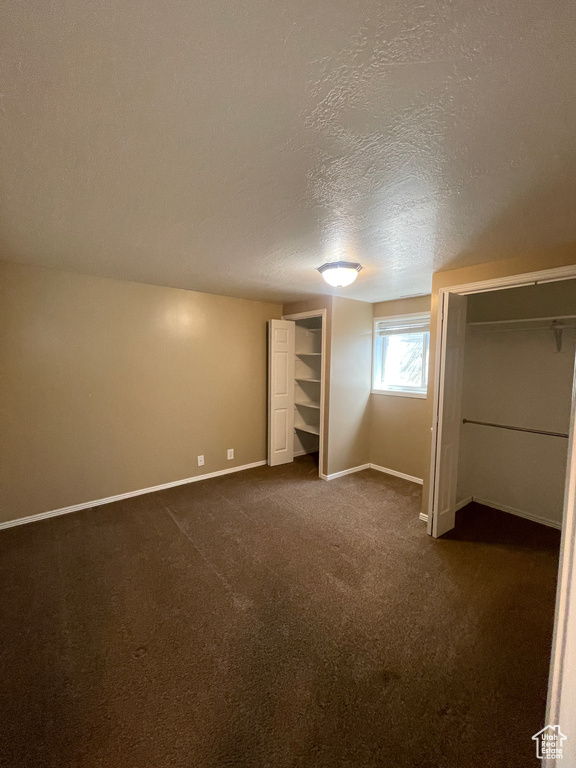 Unfurnished bedroom featuring dark carpet and a textured ceiling