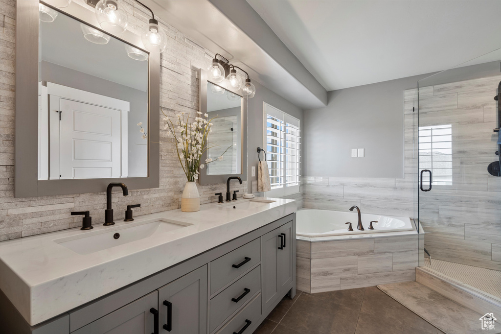 Bathroom featuring dual vanity, tile flooring, shower with separate bathtub, and backsplash