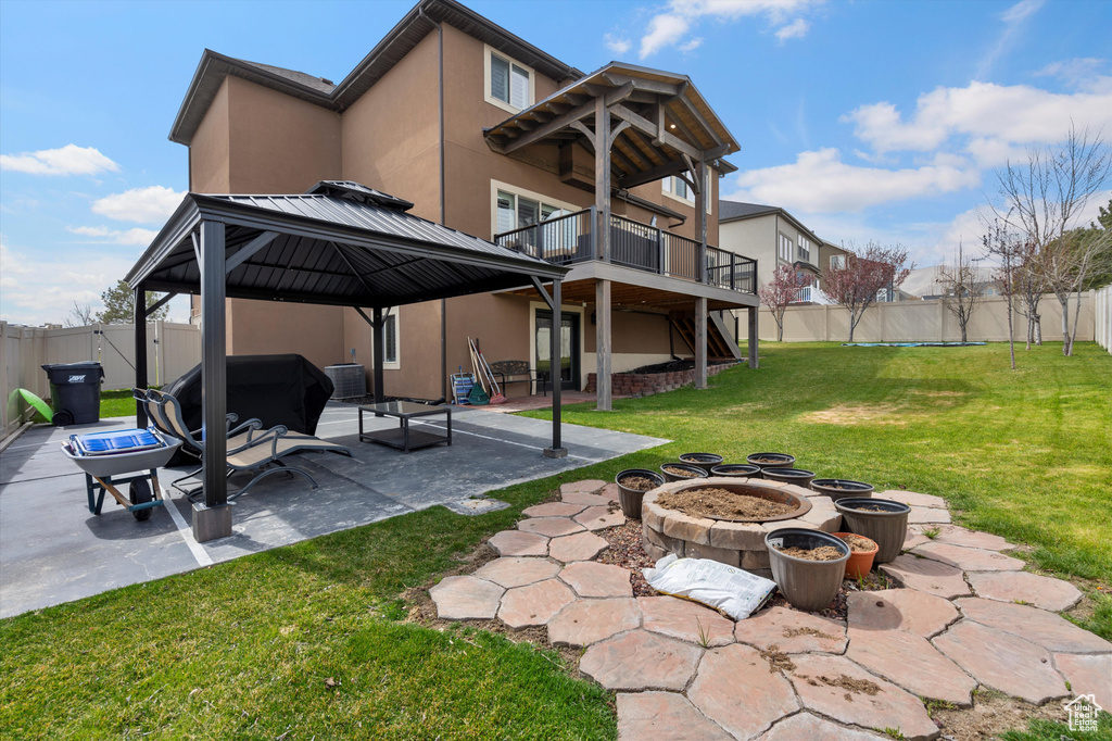 Rear view of property with an outdoor fire pit, a patio area, a lawn, and central AC unit