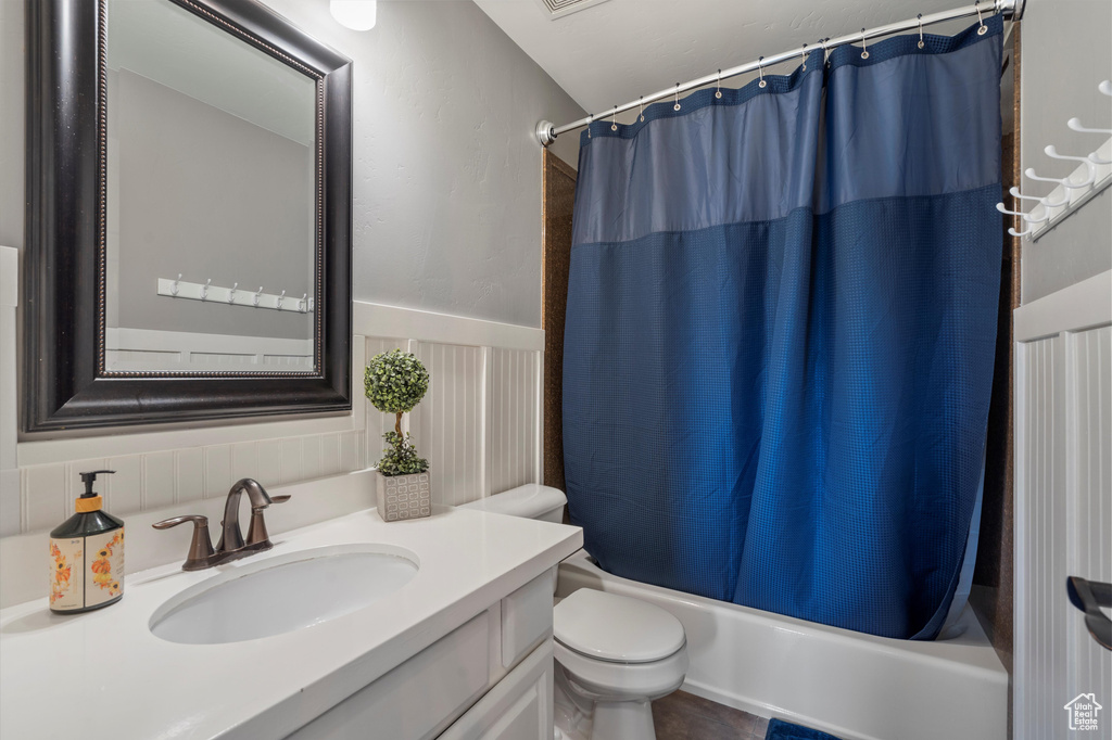 Full bathroom with oversized vanity, toilet, and shower / bathtub combination with curtain