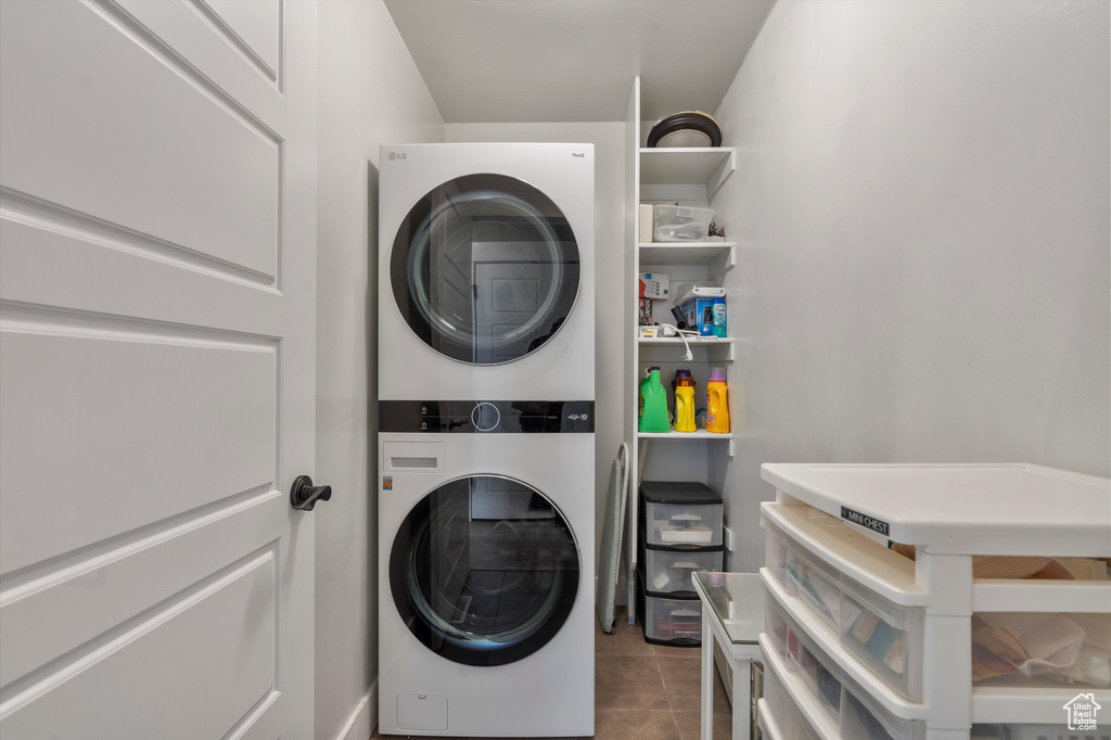 Clothes washing area with stacked washer / dryer and tile flooring