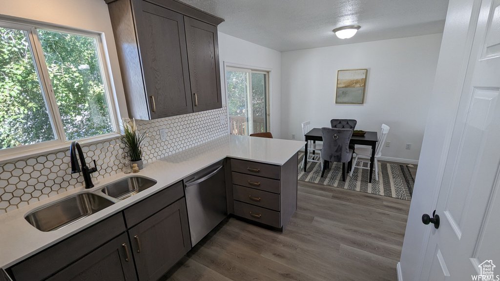 Kitchen with stainless steel dishwasher, tasteful backsplash, dark hardwood / wood-style flooring, sink, and kitchen peninsula