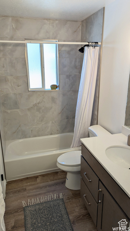 Full bathroom featuring shower / tub combo with curtain, toilet, vanity, and wood-type flooring