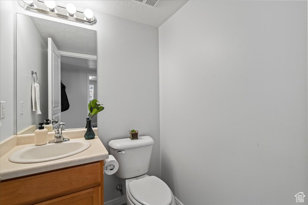 Bathroom featuring toilet, vanity, and a textured ceiling