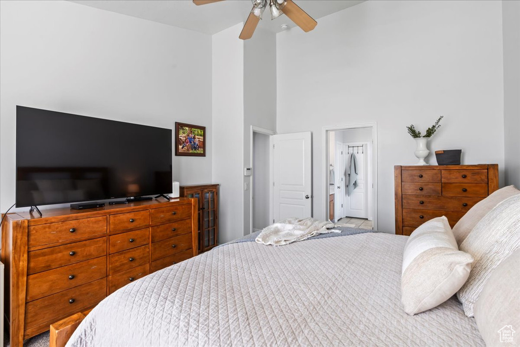 Bedroom featuring ceiling fan, ensuite bath, and a high ceiling