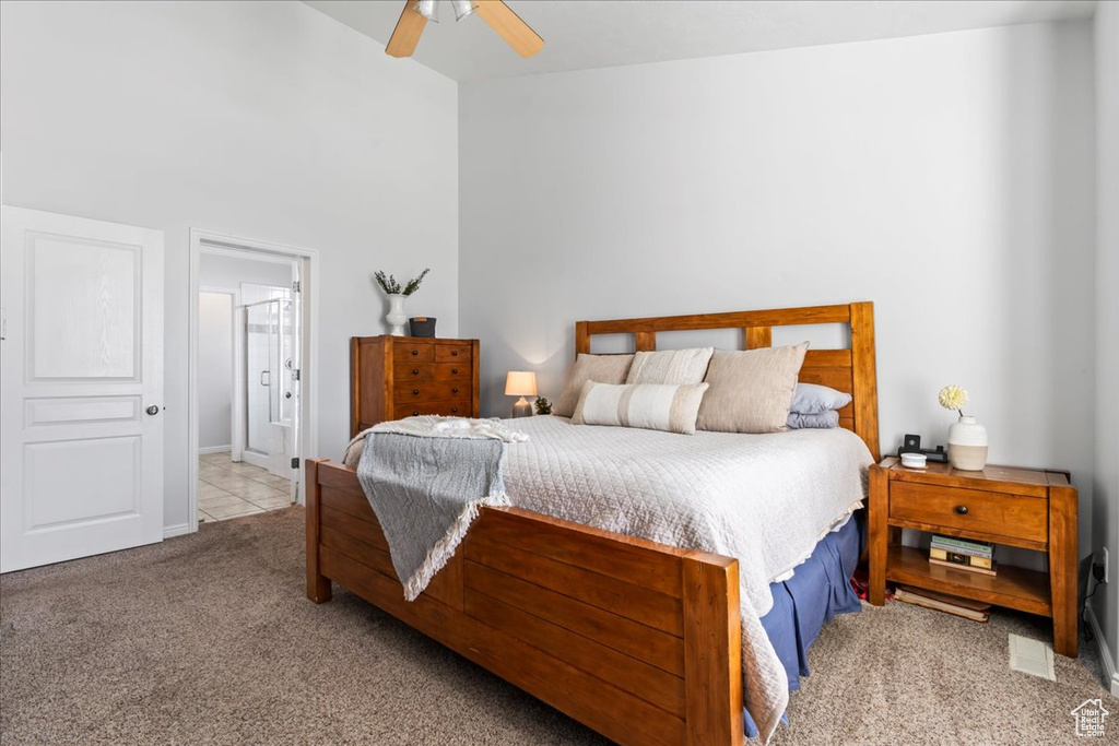 Bedroom featuring ceiling fan, light colored carpet, and ensuite bathroom