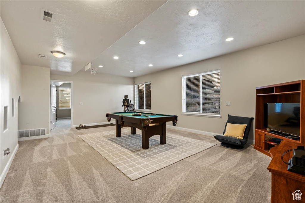 Recreation room featuring billiards, a textured ceiling, light colored carpet, and a healthy amount of sunlight