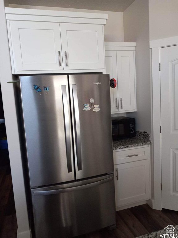 Kitchen featuring white cabinets, dark wood-type flooring, and stainless steel fridge