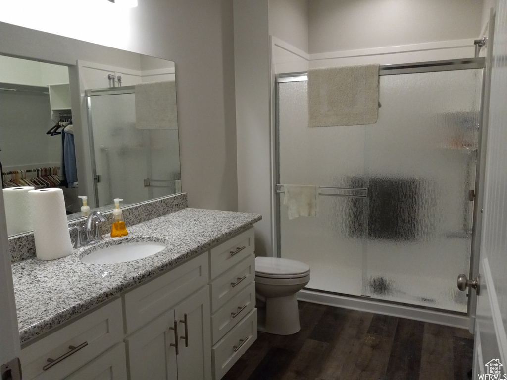 Bathroom featuring hardwood / wood-style floors, toilet, vanity, and an enclosed shower