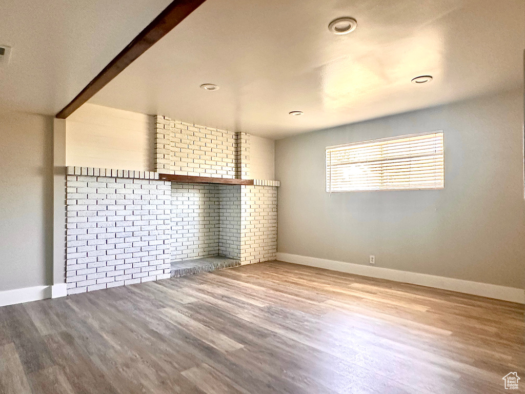 Empty room featuring light hardwood / wood-style floors and a brick fireplace