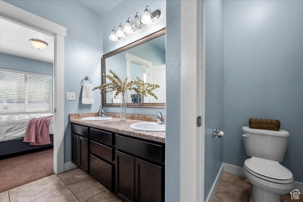 Bathroom with dual sinks, oversized vanity, tile flooring, and toilet