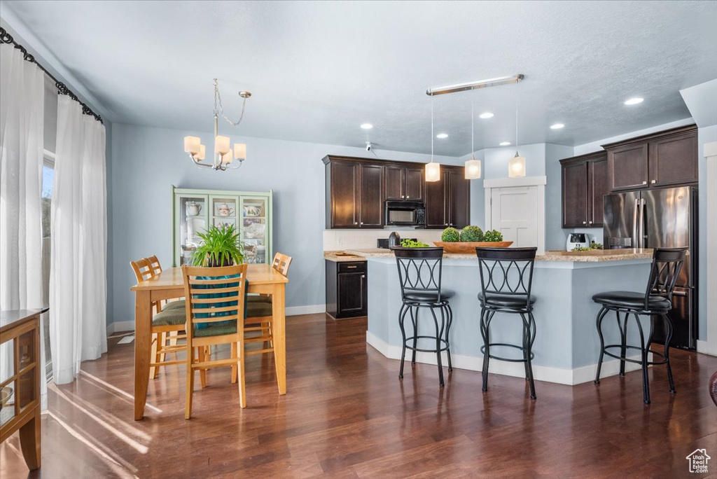 Kitchen featuring dark hardwood / wood-style floors, a breakfast bar, and hanging light fixtures