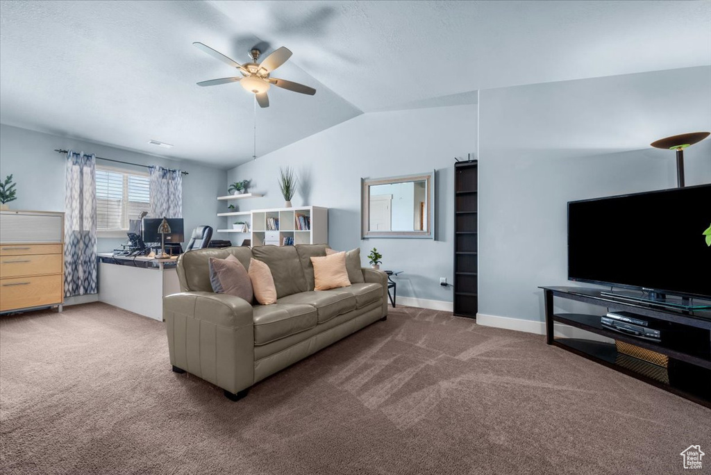 Living room with ceiling fan, vaulted ceiling, and dark colored carpet