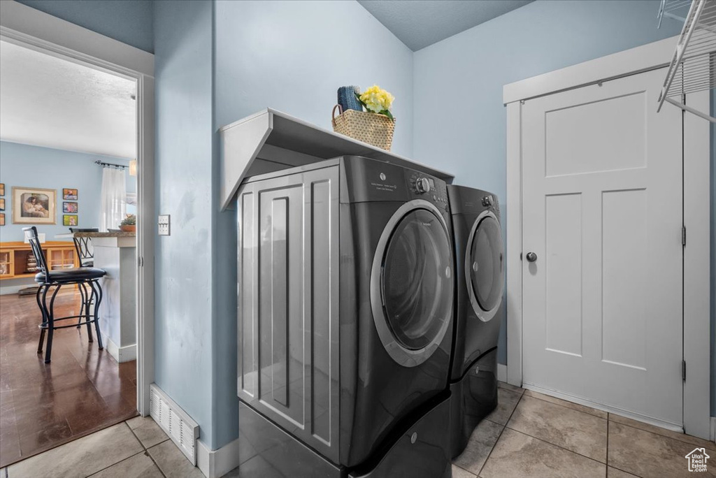 Washroom with washer and clothes dryer and light tile floors
