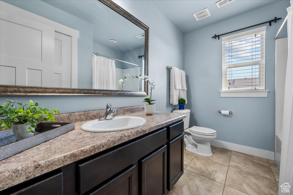 Bathroom featuring toilet, vanity with extensive cabinet space, and tile floors