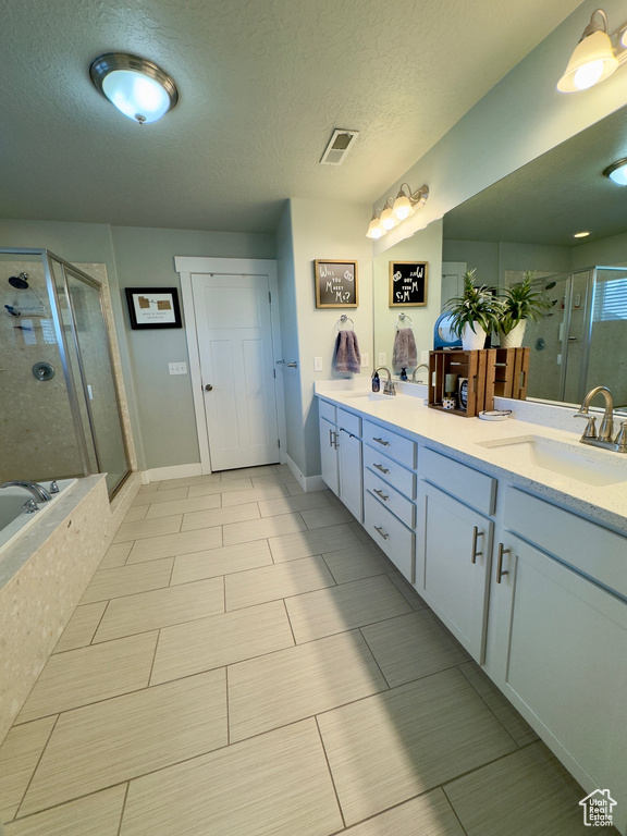 Bathroom featuring separate shower and tub, tile floors, and a textured ceiling