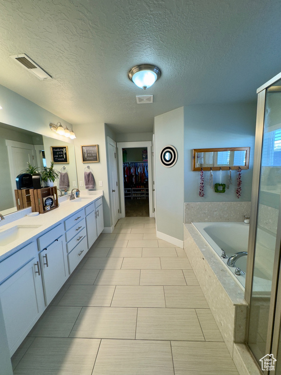 Bathroom featuring dual bowl vanity, a textured ceiling, tile floors, and independent shower and bath