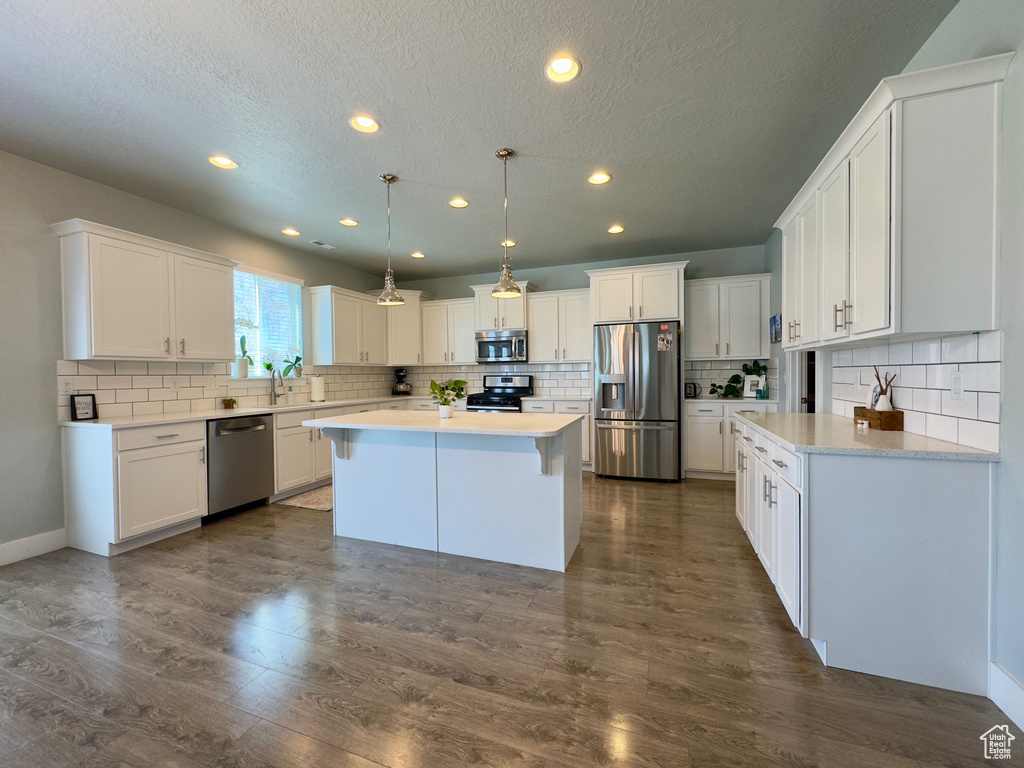 Kitchen featuring dark hardwood / wood-style flooring, tasteful backsplash, a center island, and stainless steel appliances
