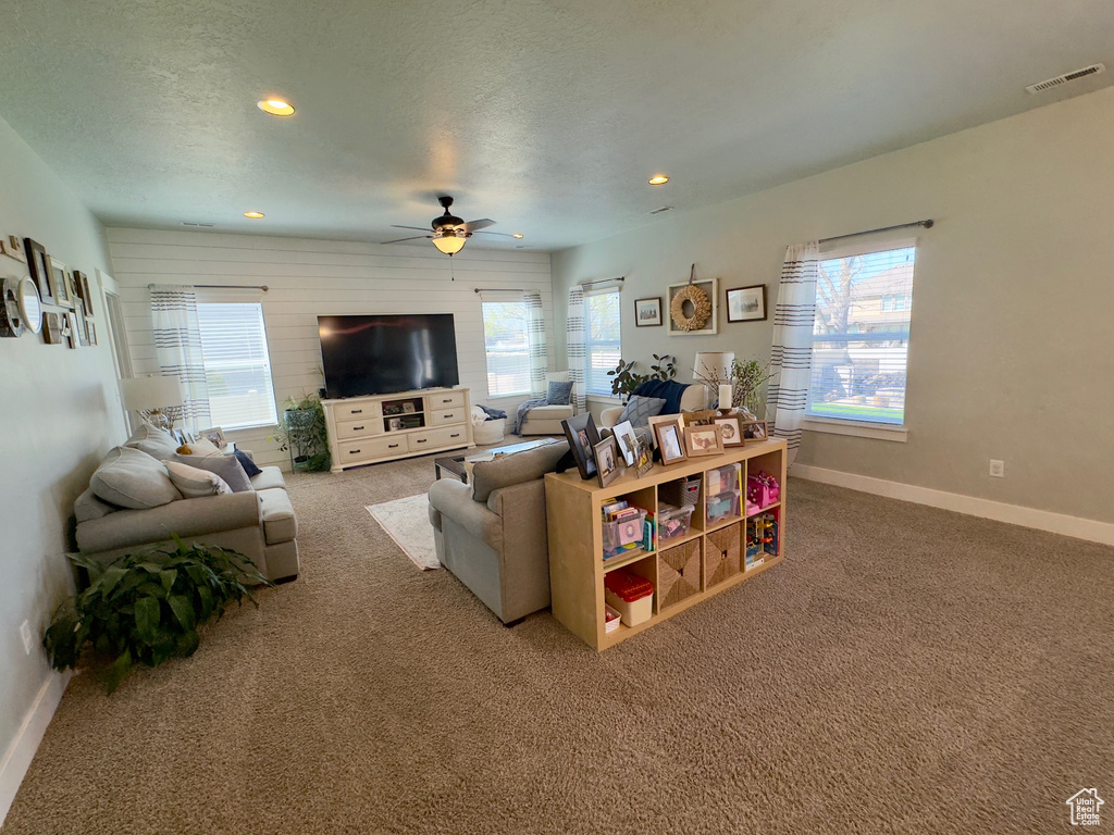 Living room featuring ceiling fan, carpet flooring, and a healthy amount of sunlight