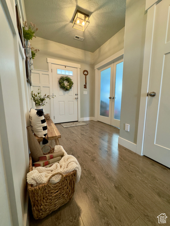 Entryway featuring a textured ceiling, french doors, and dark wood-type flooring