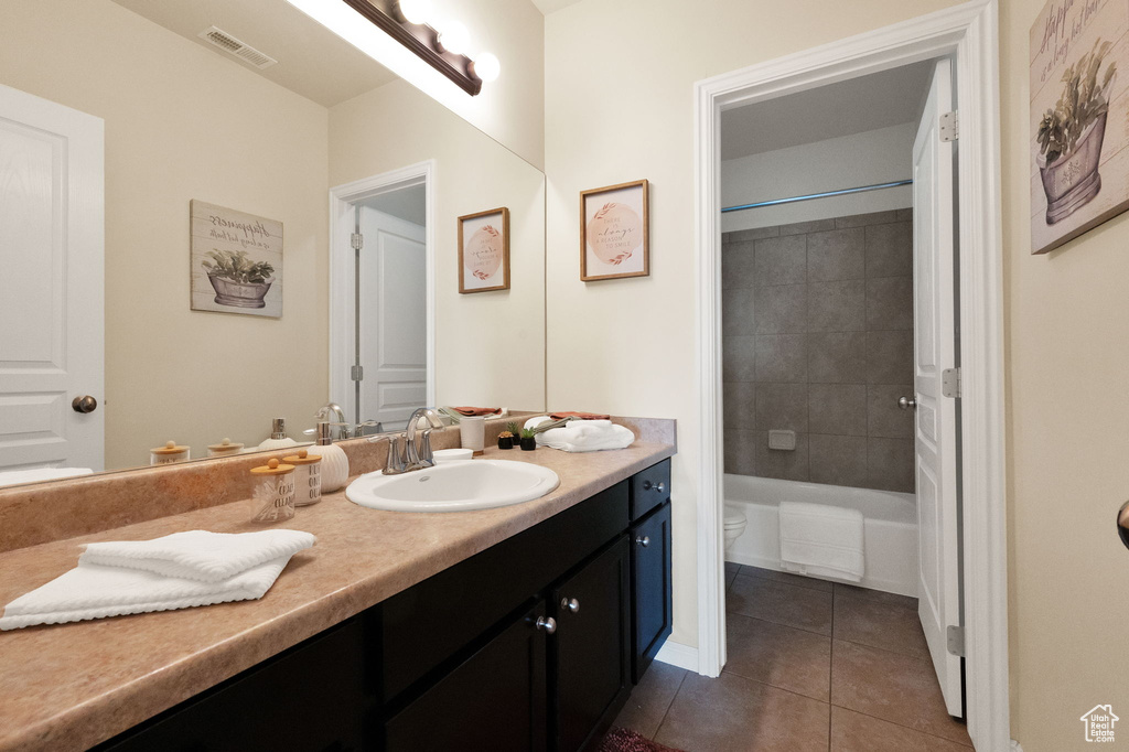 Full bathroom featuring tile flooring, toilet, oversized vanity, and tiled shower / bath