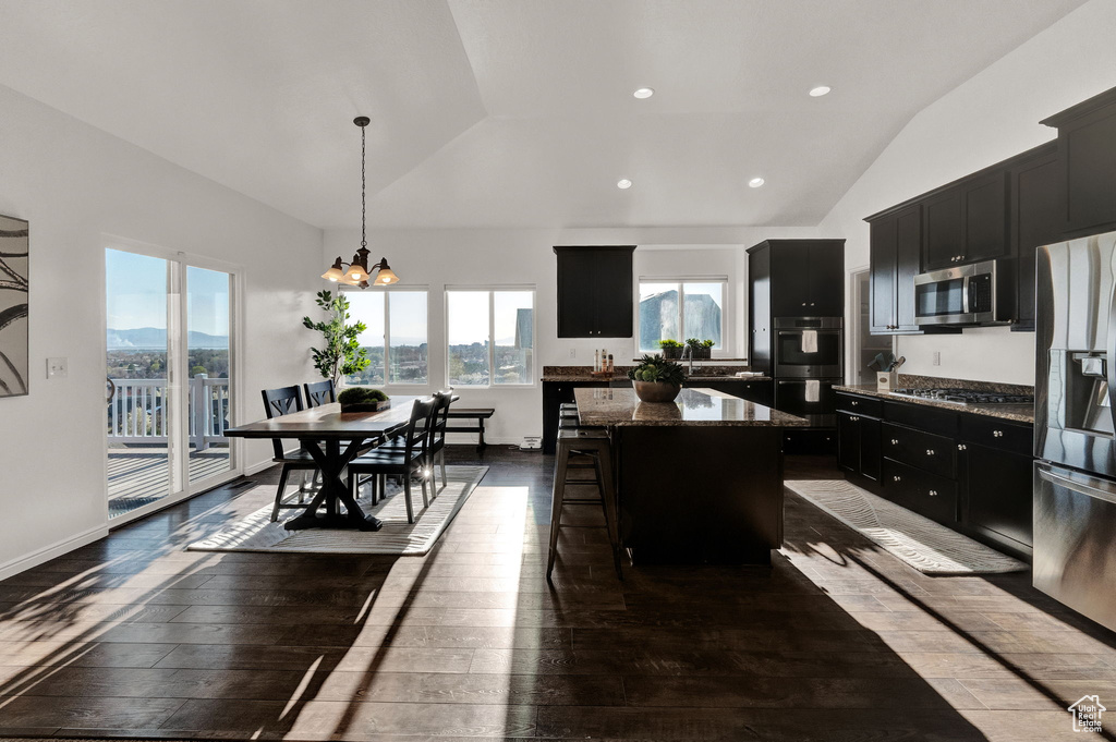 Kitchen featuring appliances with stainless steel finishes, hanging light fixtures, a center island, a breakfast bar, and dark hardwood / wood-style floors
