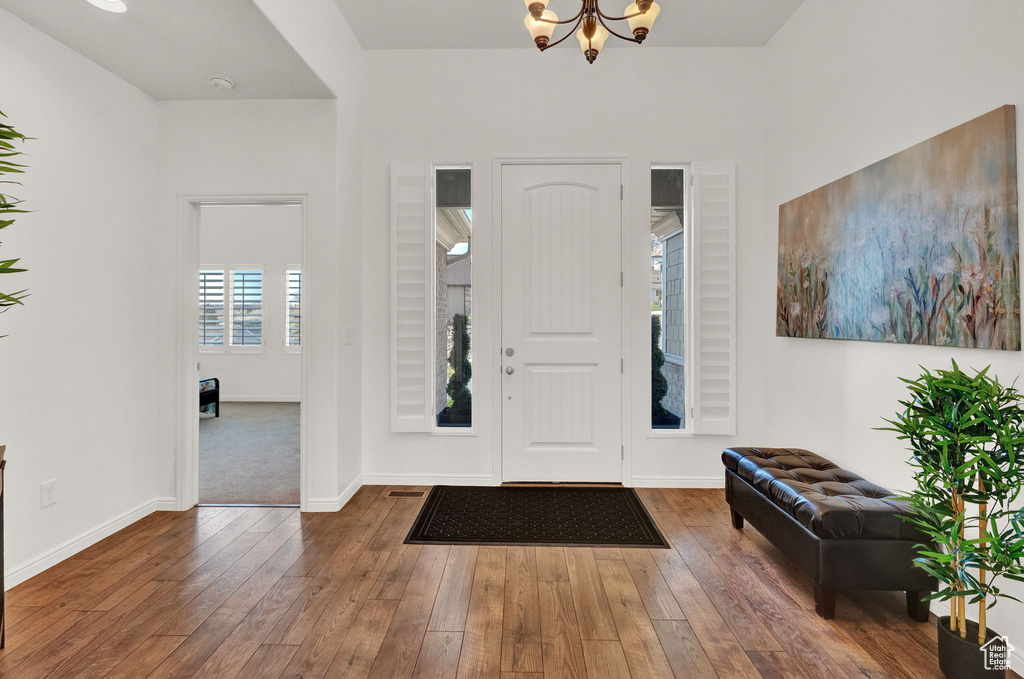 Entrance foyer with dark hardwood / wood-style flooring and an inviting chandelier