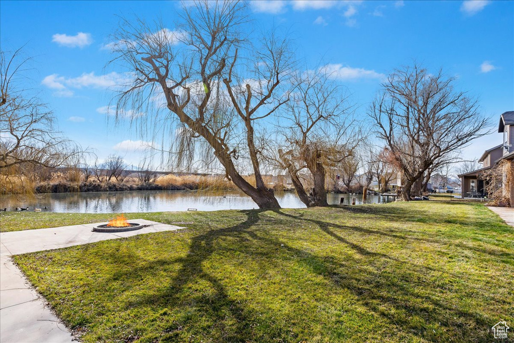 Surrounding community featuring an outdoor fire pit, a water view, and a yard