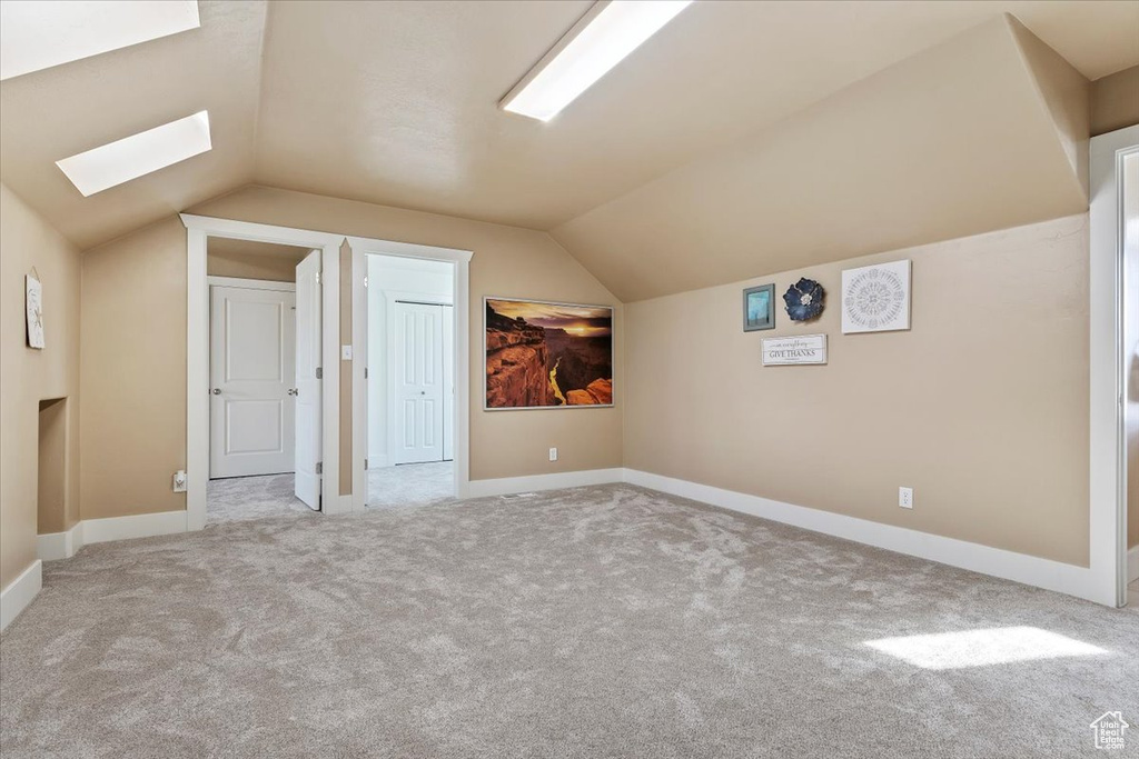 Bonus room with light carpet and vaulted ceiling with skylight