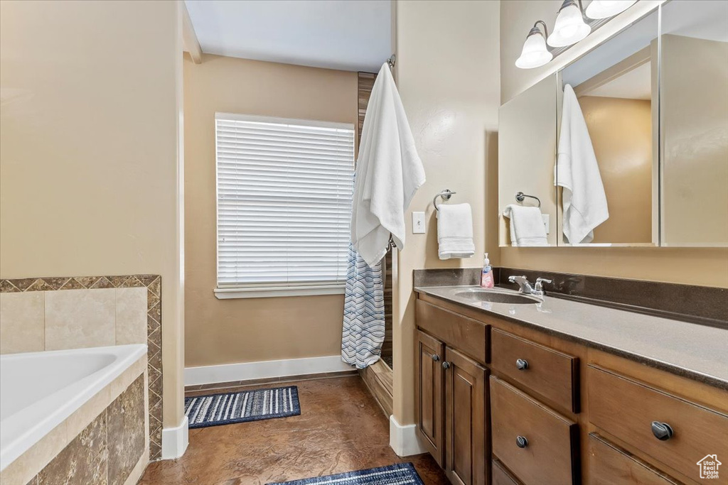 Bathroom featuring tiled bath, oversized vanity, and tile flooring