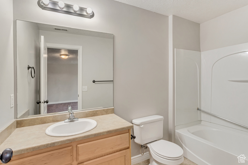 Full bathroom featuring shower / washtub combination, a textured ceiling, toilet, and vanity with extensive cabinet space