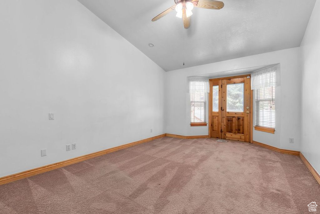 Spare room featuring ceiling fan, lofted ceiling, and light carpet
