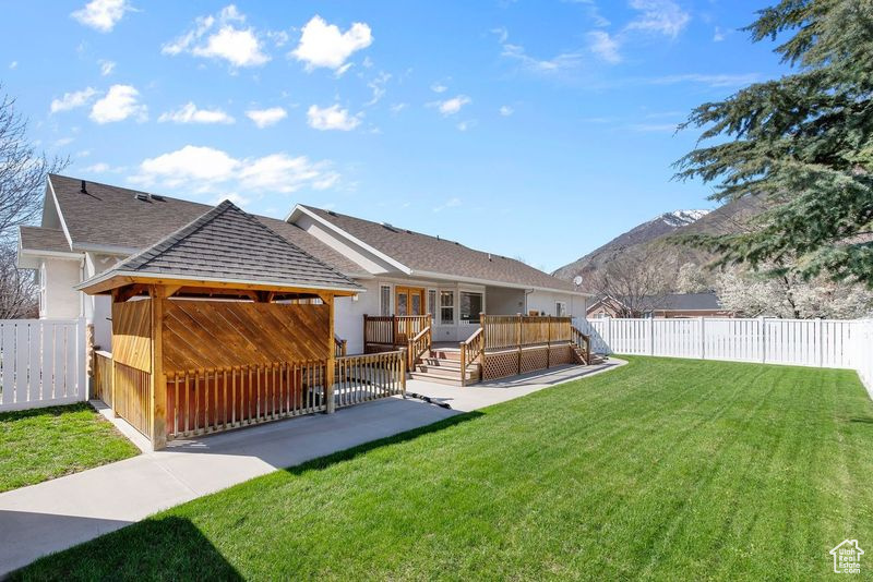 Rear view of property with a deck with mountain view and a yard