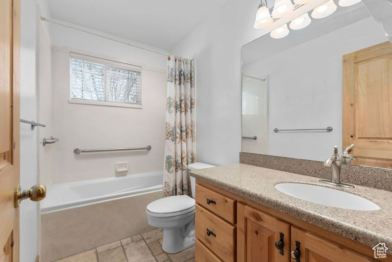Full bathroom with toilet, shower / tub combo with curtain, large vanity, and tile floors